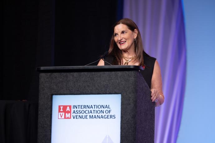 a photo of Kerry Painter she is standing behind a podium with the IAVM logo on it